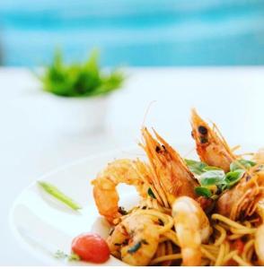 a plate of shrimp and pasta on a table at Fisilanis Beachfront Hotel in Logaras