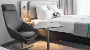 ein Schlafzimmer mit einem Bett, einem Stuhl und einem Tisch in der Unterkunft Holiday Inn Express Düsseldorf - Hauptbahnhof, an IHG Hotel in Düsseldorf