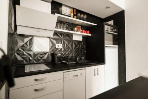 a kitchen with white cabinets and black walls at Chill Out Apartment in Novi Sad