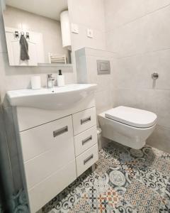 a white bathroom with a sink and a toilet at Chill Out Apartment in Novi Sad