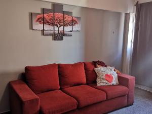 un sofá rojo en una sala de estar con una pintura de árbol en La Morada en Mendoza