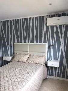 a bedroom with a bed and a striped wall at Los 7 Deseos in Tandil