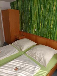 ein Bett mit zwei Kissen und einem grünen Vorhang in der Unterkunft Hotel-Restaurant Babylon in Dierdorf