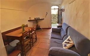 Ca lEsperrucat Acogedora casa de pueblo Tranquila y bien comunicada في Argelaguer: غرفة معيشة مع أريكة زرقاء وطاولة