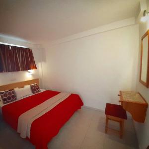 a small bedroom with a red bed and a table at Apartamentos Calma in Playa del Ingles