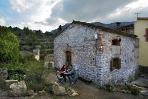Casa Rural LEra في Torre de Fontaubella: جلوس شخصين على طاولة خارج مبنى حجري
