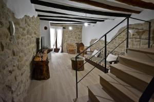 sala de estar con escaleras y pared de piedra en Casa del Tio Vicente, en Calaceite