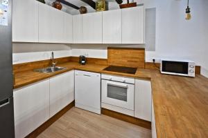 a kitchen with white cabinets and a sink and a microwave at Casa del Tio Vicente in Calaceite