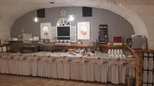 a long table in a large room with a table with drinks on it at Guest House Romantika Panzio in Gyula