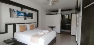 a bedroom with a white bed and a bathroom at Hotel Beach Energy 5th Av in Playa del Carmen