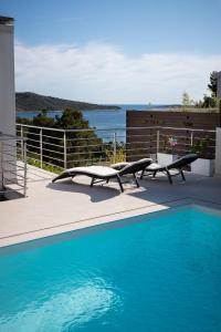 a swimming pool with two lounge chairs next to a fence at Entire private top floor with own pool and entrance in Primošten