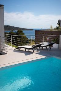 a swimming pool with two lounge chairs next to a fence at Entire private top floor with own pool and entrance in Primošten