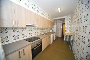 a kitchen with wooden cabinets and tiles on the wall at Coimbra vista mar Orangecosta in Benicàssim