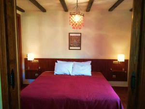 1 dormitorio con 1 cama con manta roja y lámpara de araña en Casa Rural FranciaQuilamas en Santibáñez de la Sierra