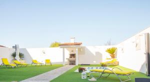 a backyard with a green lawn and yellow chairs at CASA LAS PALMERAS in Cambados