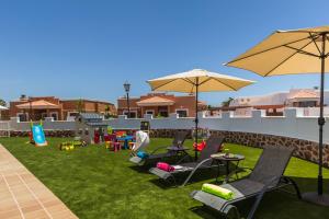 einen Garten mit Stühlen, Tischen und Sonnenschirmen in der Unterkunft Perfect for family holidays with private pool, near beach and golf- Villa Ashley in Costa de Antigua