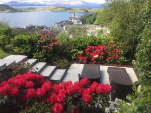 um jardim com dois bancos e flores vermelhas em Tigh Beag em Oban