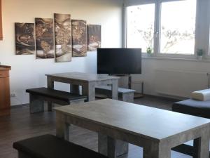 ein Wohnzimmer mit 2 Tischen und einem Flachbild-TV in der Unterkunft Pension Gästehaus Kautz in Karlsruhe
