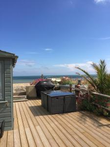 a wooden deck with a table on the beach at Beautiful 4 Bed Beach House in Pevensey