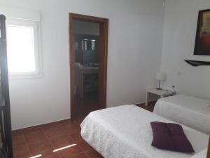 1 dormitorio blanco con 2 camas y ventana en HOTEL RURAL FINCA LA CALERA lanzarote, en Güime