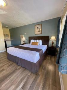 a large bedroom with a large bed and wooden floors at Palm Tropics Motel in Glendora