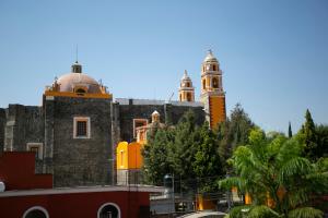 an old building with two towers on top of it at Majikal B&B - Jacaranda in Cholula +6 photos