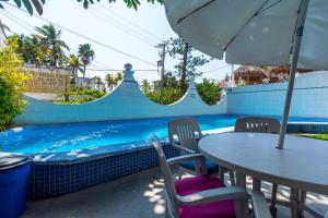 een tafel met een parasol naast een zwembad bij Hotel Delfin in Barra de Navidad