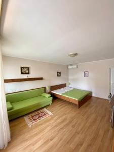 una camera con un divano verde e un letto di Apartmánový dom Flóra a Veľký Meder