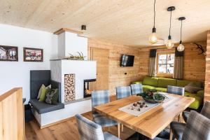 a dining room with a wooden table and a green couch at Bergseegut Chalet und Apartment in Wagrain