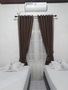 two beds in a room with brown curtains at BUMiMi HOMESTAY in Painan