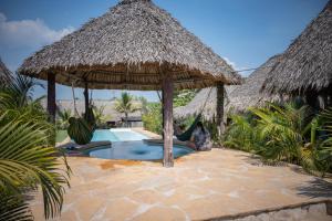 a person sitting in a hammock under a thatched umbrella at Pacifico El Paredon in El Paredón Buena Vista