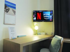einen Schreibtisch in einem Zimmer mit einem TV an der Wand in der Unterkunft Appart'AZUR Haguenau - Hyper centre Mairie - Parking facile - Wifi - Lit confort Kingsize in Haguenau