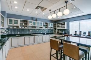 a kitchen with white cabinets and a bar with stools at Hyatt Place Fort Worth/Hurst in Hurst