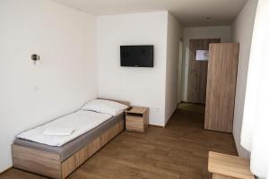 1 dormitorio con 1 cama y TV en la pared en Vegas Hriňová Penzión en Hriňová