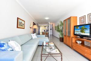 sala de estar con sofá azul y TV en Luxury BeachFront Mogan en Puerto de Mogán