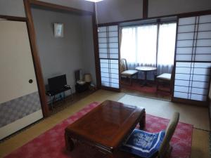 sala de estar con mesa, sillas y ventanas en Kinreisou, en Hakone