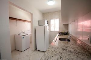 cocina con nevera blanca y fregadero en Condomínio Bromélias - APT 2 QUARTOS, en Bombinhas