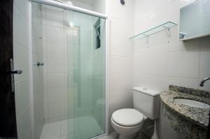 y baño con ducha, aseo y lavamanos. en Condomínio Bromélias - APT 2 QUARTOS, en Bombinhas