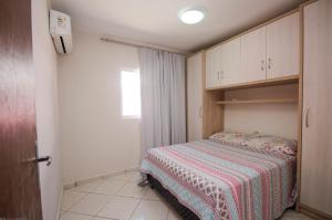 Dormitorio pequeño con cama con manta a rayas en Condomínio Bromélias - APT 2 QUARTOS, en Bombinhas