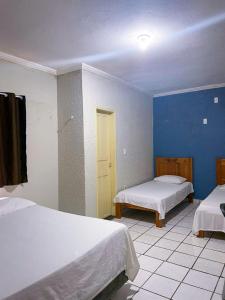 um quarto com duas camas e uma porta amarela em Pousada Pilotos em Itapipoca