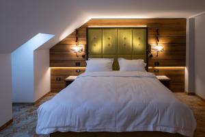una camera da letto con un grande letto bianco con due lampade di Hotel Belmont a Sinaia