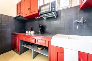 a kitchen with red cabinets and a sink at La Dame de Coeur - 1 chambre in Brive-la-Gaillarde