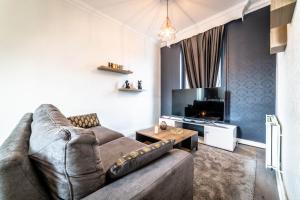 ein Wohnzimmer mit einem Sofa und einem TV in der Unterkunft POMPIDOU #2 - Chic & Elégant - 1 chambre in Brive-la-Gaillarde