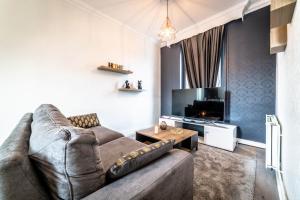 a living room with a couch and a tv at Le Temps Éternel - 1 chambre in Brive-la-Gaillarde