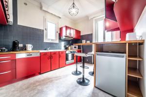 a kitchen with red cabinets and a stool in it at Le Temps Éternel - 1 chambre in Brive-la-Gaillarde