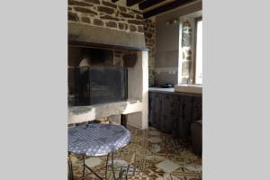 a kitchen with a fireplace and two stools in a room at La Cahute in La Forêt-Auvray