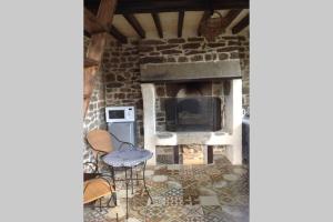 a living room with a stone fireplace with a table and chairs at La Cahute in La Forêt-Auvray
