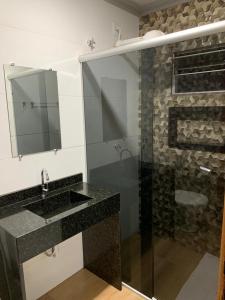 a bathroom with a sink and a shower with a mirror at Raludi Hotel in Barcarena