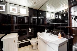 Un baño con azulejos negros, inodoro y lavabo. en Town Center Rustaveli ApartHotel, en Tiflis 9 fotos más