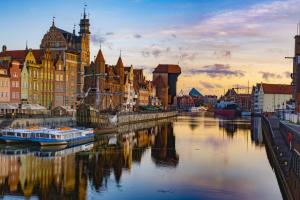 een stad met gebouwen en een rivier met boten bij Swish Apartment in Gdańsk